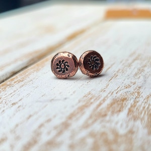 May include: A white ceramic mug with a black handle and the text "But First, Coffee" in a black, handwritten-style font. The mug is on a white surface.