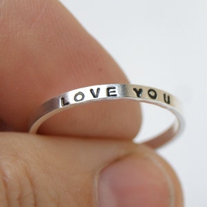 May include: A silver ring with the words "LOVE YOU" engraved on the band.