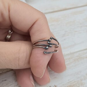 Puede incluir: Un anillo envolvente plateado con un dise&ntilde;o &uacute;nico. El anillo presenta m&uacute;ltiples bandas que se envuelven alrededor del dedo, cada una terminando en una peque&ntilde;a esfera texturizada. El dise&ntilde;o del anillo recuerda a un grupo de cerillas.