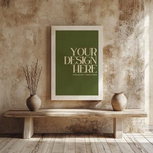 May include: A framed print with the text "YOUR DESIGN HERE" on a green background. The print is displayed on a wooden bench with two vases and dried plants. The wall behind the bench has a textured, neutral color.