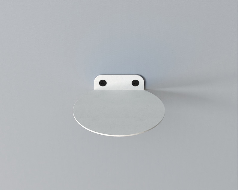 May include: White metal shelf with a rounded edge, mounted to a wall with two black screws.