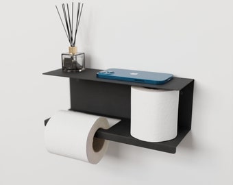 May include: A black metal shelf with a toilet paper holder and a small shelf above. A roll of toilet paper is on the holder, and a smartphone is on the top shelf. A small glass bottle with reeds is on the top shelf.