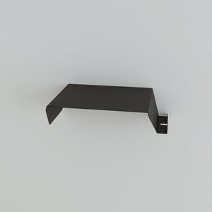 A black metal shelf with a minimalist design. The shelf has a flat top and a downward-sloping front edge. A small, vertical support with a rectangular cutout is on the right side. The shelf is designed to be mounted on a wall.