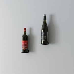May include: Two bottles of wine mounted on a wall with black metal holders. The bottle on the left is red wine with a gold label that says "Silverveil". The bottle on the right is white wine with a black label that says "TRACEROW" and "Sonoma Valley".