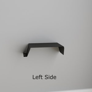 A black metal shelf with a minimalist design. The shelf is mounted on a light gray wall. The text "Left Side" is displayed below the shelf.