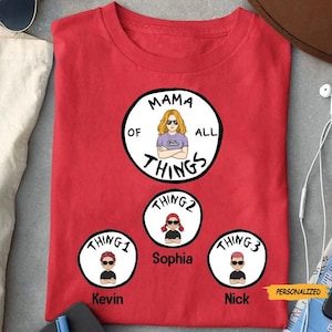 May include: Red t-shirt with a white circle that says "Mama of All Things" with a cartoon woman inside. Below the circle are three smaller circles with cartoon people and the text "Thing 1", "Thing 2", and "Thing 3". The names Kevin, Sophia, and Nick are written below the circles.