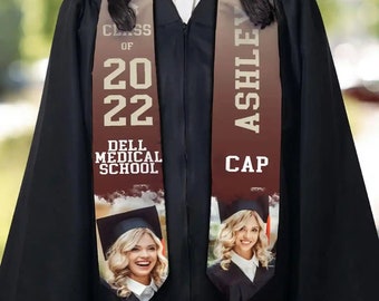 May include: A graduation sash with a brown and beige ombre design. The left side features the text "Class of 2022 Dell Medical School" and a photo of a woman. The right side features the text "Ashley Cap" and a photo of a woman.