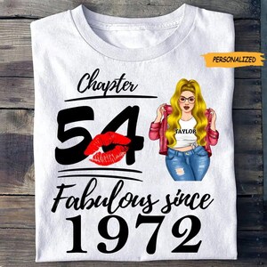 Peut inclure: T-shirt blanc avec le texte "Chapter 54 Fabulous since 1972". Le chiffre 54 est en gros caractères noirs avec une bouche rouge. Une illustration de femme blonde à lunettes est également sur le t-shirt. Le mot "Personalized" est dans un encadré jaune.
