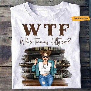 Peut inclure: T-shirt blanc avec le texte "WTF Who's Turning fifty-six?" en marron et noir. Le t-shirt présente un graphisme d'une femme portant des lunettes de soleil et une veste en jean. Le mot "PERSONNALISÉ" est dans un encadré jaune.