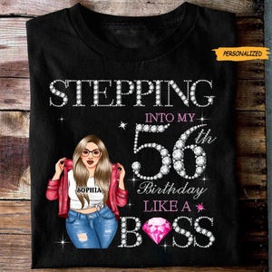 Peut inclure: T-shirt noir avec l'inscription "STEPPING INTO MY 56th BIRTHDAY LIKE A BOSS" en strass. Le t-shirt présente une illustration de femme portant des lunettes, une veste rouge et un jean. Le nom "Sophia" est sur le t-shirt.