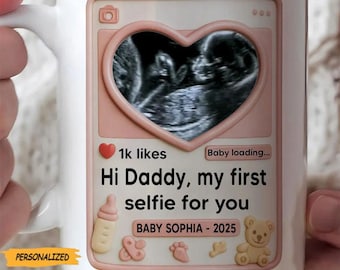 May include: White ceramic mug with a pink design featuring a baby ultrasound image in a heart shape. Text reads "Hi Daddy, my first selfie for you" and "Baby Sophia - 2025". Includes baby-themed icons.