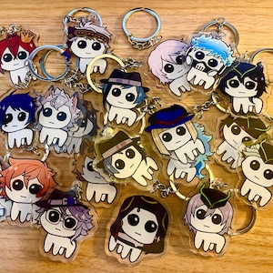 Può includere: Una collezione di 15 portachiavi con personaggi dei cartoni animati colorati. Ogni portachiavi presenta un personaggio diverso con espressioni facciali e vestiti unici. I portachiavi sono realizzati in acrilico trasparente e hanno anelli portachiavi in metallo argentato.