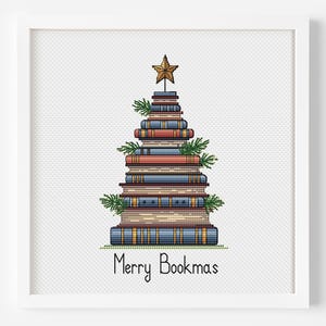 May include: A framed print features a Christmas tree made of stacked books. The books are in various colors, with a gold star on top and sprigs of greenery. The text "Merry Bookmas" is at the bottom.