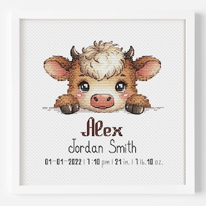 May include: A framed cross-stitch featuring a cartoon cow with brown and cream fur. The cow's name, "Alex Jordan Smith," is below, along with birth details: 01-01-2022, 7:10 pm, 21 inches, 1 lb. 10 oz. The artwork is set against a white background.