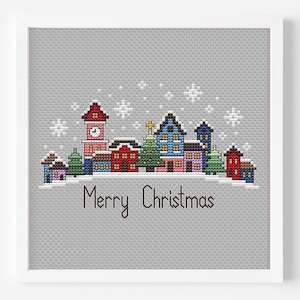 Könnte beinhalten: Kreuzstichmuster eines Winterdorfes mit Schneefall, einem Weihnachtsbaum und dem Text "Frohe Weihnachten".