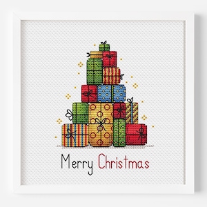 Op de afbeelding: Een ingelijst kruissteekontwerp met een stapel kleurrijke cadeauverpakkingen in de vorm van een kerstboom. De cadeaus zijn in verschillende kleuren, met de tekst "Merry Christmas" eronder.