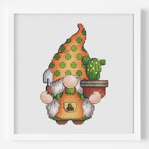 May include: A cross-stitch pattern of a gnome wearing a green and orange hat with white polka dots, holding a small shovel and a potted cactus.