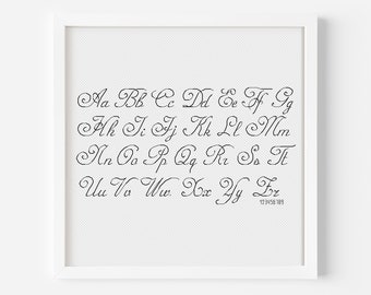 May include: A framed print of a cursive alphabet in black ink on a white background. The letters are arranged in rows, with each letter paired with its lowercase counterpart. The print includes the numbers 123456789 at the bottom.