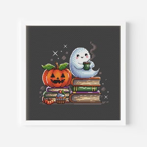 May include: Cross-stitch art of a friendly ghost sipping from a mug, perched atop a stack of books next to a carved pumpkin. The artwork has a Halloween theme with a dark gray background and a white frame.
