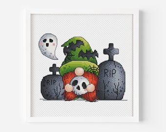 Op de afbeelding: Een ingelijste kruissteek met een Halloween-kabouter met een groene heksenhoed met vleermuisuitsparingen, een schedelgezicht en oranje haar. Twee grijze grafstenen met "RIP" staan aan weerszijden van de kabouter en een geest zweeft erboven.