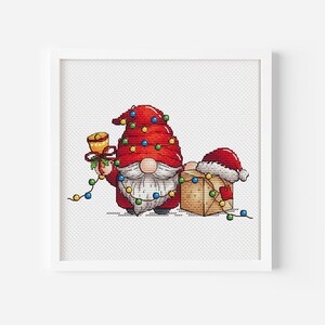 May include: A red and white Christmas gnome holding a bell and a gift box with a red bow. The gnome is surrounded by colorful Christmas lights.