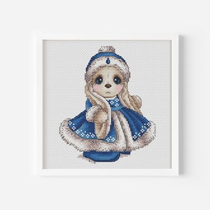 May include: Cross stitch pattern of a cute cartoon bear wearing a blue winter coat and hat with white fur trim.