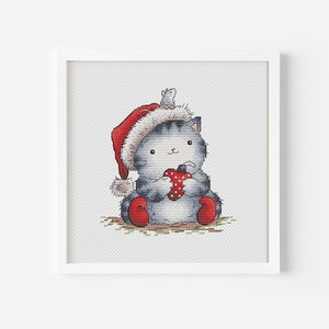 Könnte beinhalten: Eine graue Katze mit einem roten Weihnachtsmann-Hut und einem roten Herzen in den Pfoten. Eine kleine graue Maus sitzt auf dem Kopf der Katze. Die Katze sitzt auf einem grün-braunen Hintergrund.