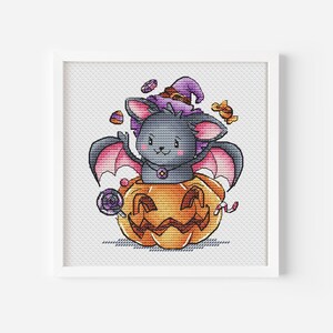 Op de afbeelding: Een schattige paarse en zwarte vleermuis met een heksenhoed zit in een uitgeholde oranje pompoen. De vleermuis is omringd door snoep en andere Halloween-traktaties.