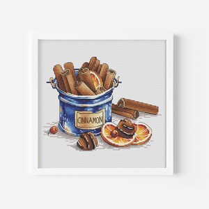 May include: A blue metal container filled with cinnamon sticks and labelled "CINNAMON". The container is sitting on a white surface with orange slices and additional cinnamon sticks.