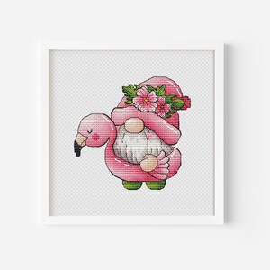 May include: A pink gnome wearing a pink flamingo float with a floral crown. The gnome is smiling and has a white beard.
