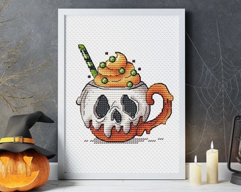 May include: A white mug with a skull design and orange dripping glaze, topped with a swirl of yellow and green frosting and green sprinkles. The mug has a handle and a green and white striped straw.