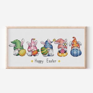 May include: Five gnomes dressed as bunnies holding Easter eggs and a carrot. The gnomes are wearing colourful hats and have white beards. The text "Happy Easter" is below the gnomes.