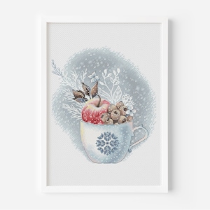 May include: A blue and white ceramic mug filled with a red apple, brown berries, and white flowers. The mug has a snowflake design and is set against a blue background with white snowflakes.