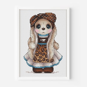 May include: Cross stitch pattern of a brown and white doll wearing a brown and blue dress with a coffee bean pattern. The doll is wearing a brown and blue hat with white polka dots.