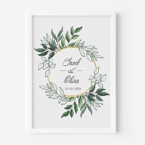 May include: A white framed cross-stitch design with a gold circle and green foliage. The text inside the circle reads "Jacob & Clara 01.01.2024".