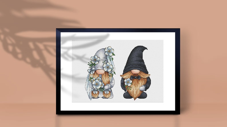May include: A cross-stitch pattern of two gnomes dressed in wedding attire. The female gnome wears a white dress with a veil and flowers, while the male gnome wears a black suit with a bow tie and flowers.
