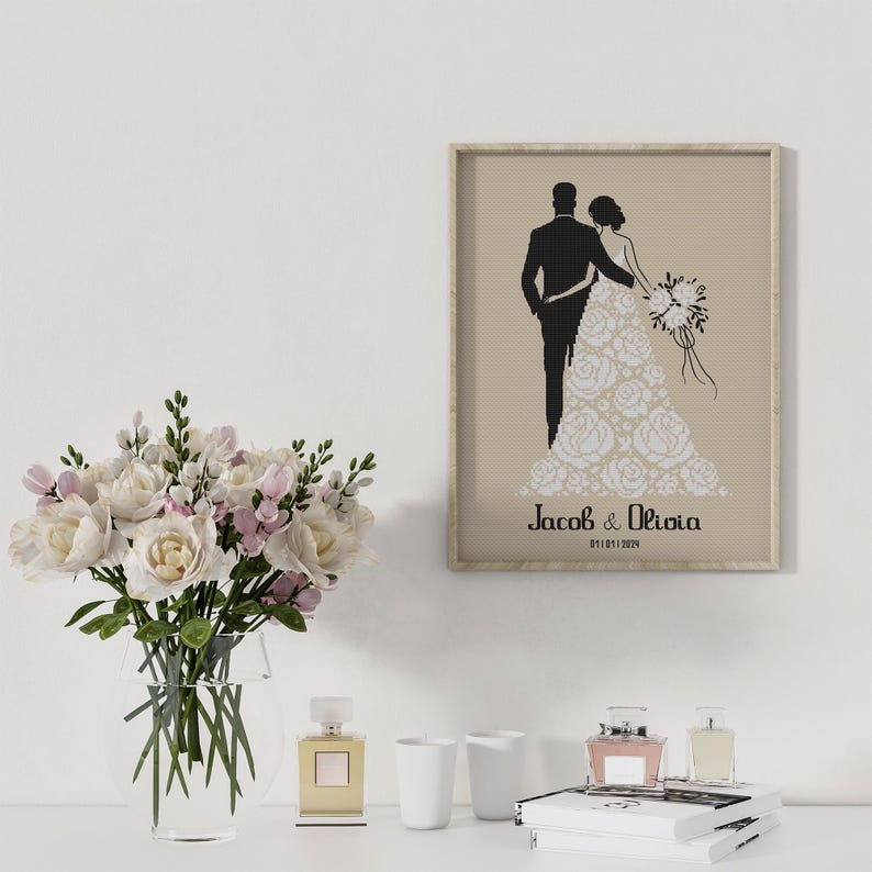 May include: A framed print with a black silhouette of a bride and groom. The bride is wearing a white dress with floral details. The groom is wearing a tuxedo. The text "Jacob & Olivia 01.01.2024" is printed below the couple.