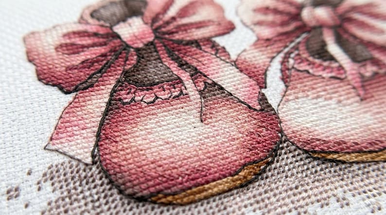 May include: Close-up of two embroidered baby shoes in shades of pink and brown. Each shoe has a large bow and decorative trim. The shoes are set against a white background with a delicate lace pattern.