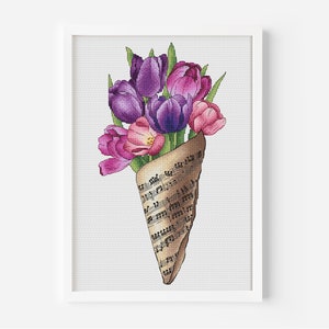 May include: A bouquet of purple and pink tulips wrapped in a sheet of music. The bouquet is arranged in a cone shape and the music sheet is folded to create a cone shape.