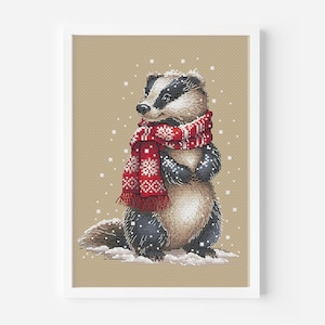 Op de afbeelding: Een kruissteekpatroon met een das die een rood-witte sjaal draagt in een besneeuwde omgeving.