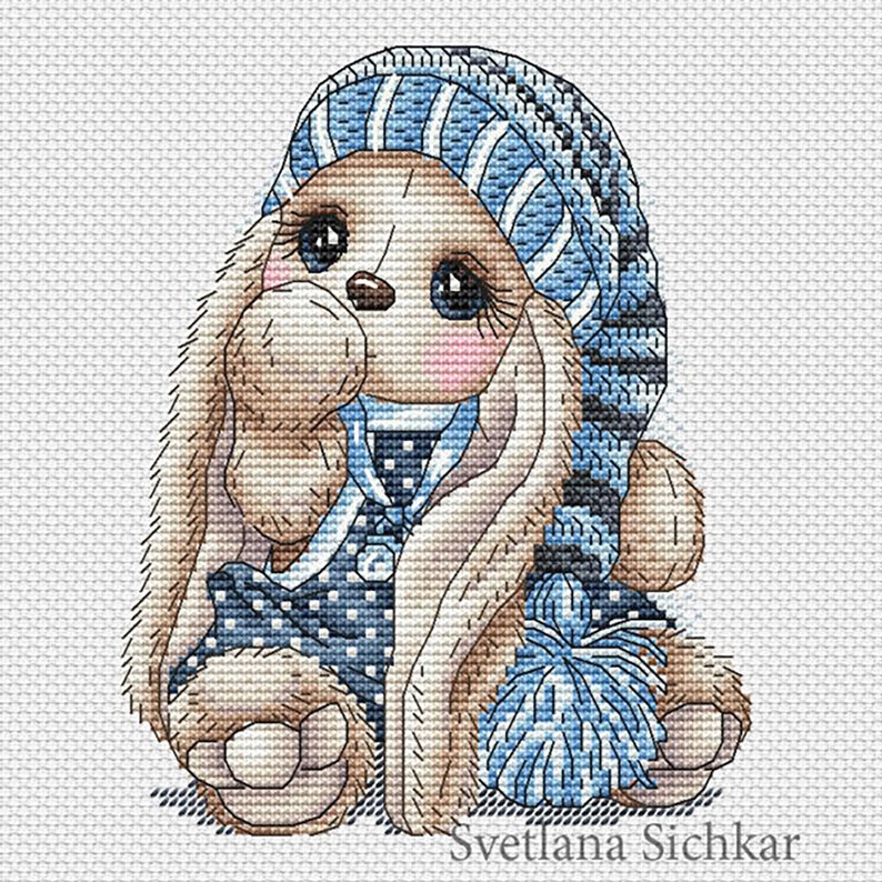Puede incluir: Un conejito marr&oacute;n y azul con un gorro a rayas azul y blanco y un pijama con lunares blancos. El conejito sostiene un pomp&oacute;n azul.