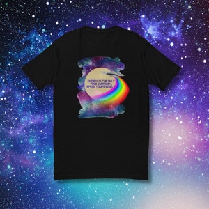 Puede incluir: Camiseta negra con estampado de galaxia y un arcoíris. El texto "ENERGY IS THE ONLY TRUE CURRENCY. SPEND YOURS WISELY" está impreso en la camiseta.