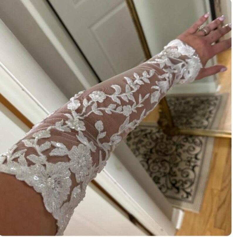 May include: White lace bridal gloves with floral embroidery and sequins.