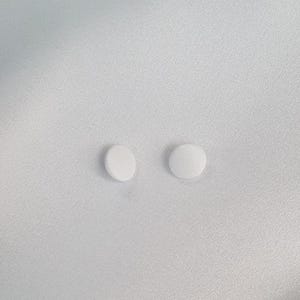 May include: Two white round buttons on a white background.