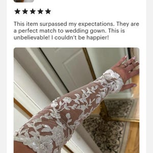 May include: White lace bridal gloves with floral embroidery and sequins. The gloves are long and extend to the elbow.
