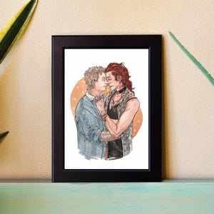May include: A framed illustration of two people embracing. The person on the left has short blond hair and is wearing a blue shirt. The person on the right has long red hair and is wearing a black tank top and a denim jacket. The background is a soft orange color with white stars.
