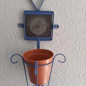 Può includere: Un portavasi da parete in metallo blu con una parte superiore a forma di cuore e una placca quadrata che recita "Millwall Football Club 1885".