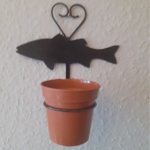 May include: Black metal fish-shaped plant hanger with a heart design. The hanger holds a small terracotta pot.