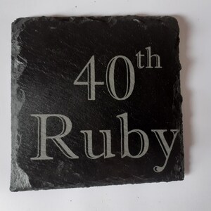 May include: A black slate plaque with the text "40th Ruby" engraved in silver lettering.