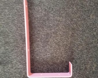 May include: A light pink, L-shaped bracket, possibly for shelving or support. The bracket is made of a solid material and has a smooth, matte finish. It features several small holes along one side for mounting.